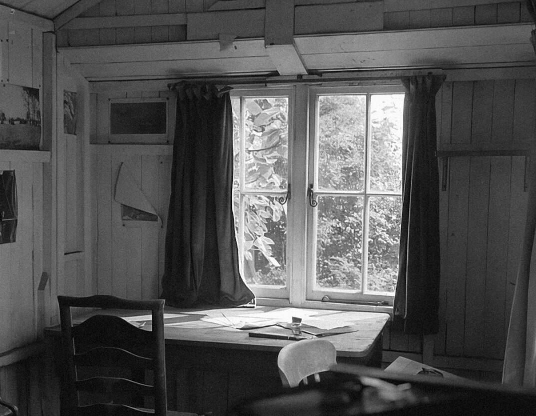 Wooden desk with open notebook and pen near a window